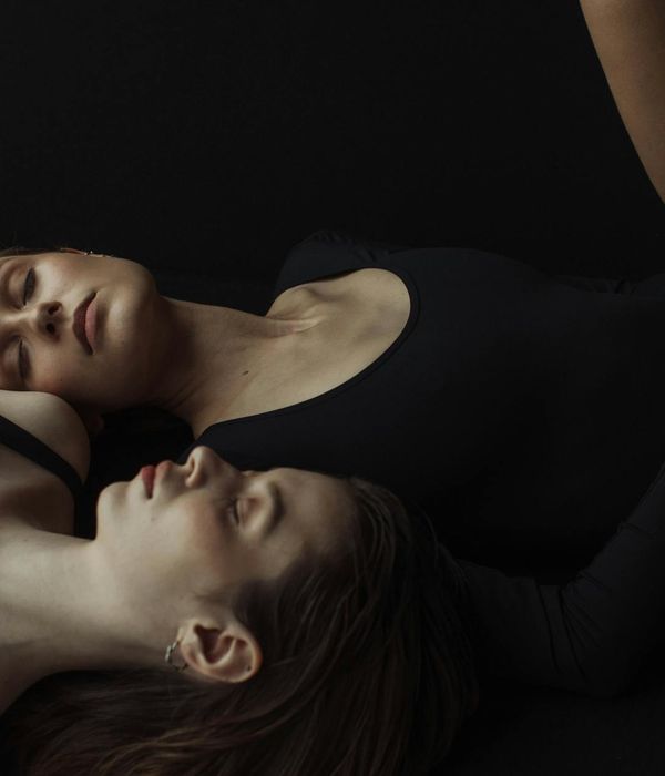 Woman in a calm yoga pose against a dark, serene background.
